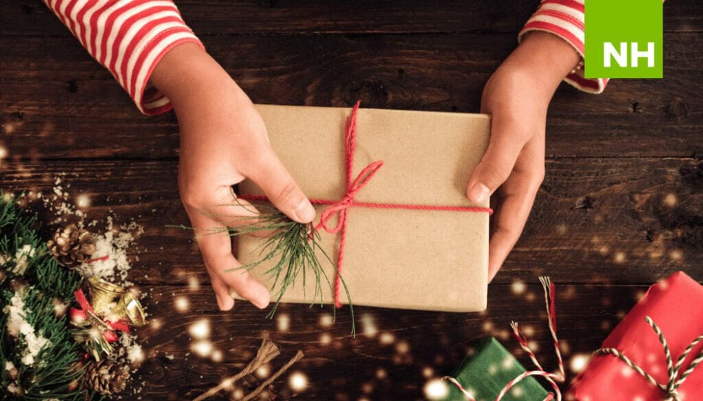 Hands holding wrapped gift with nearby holiday decor