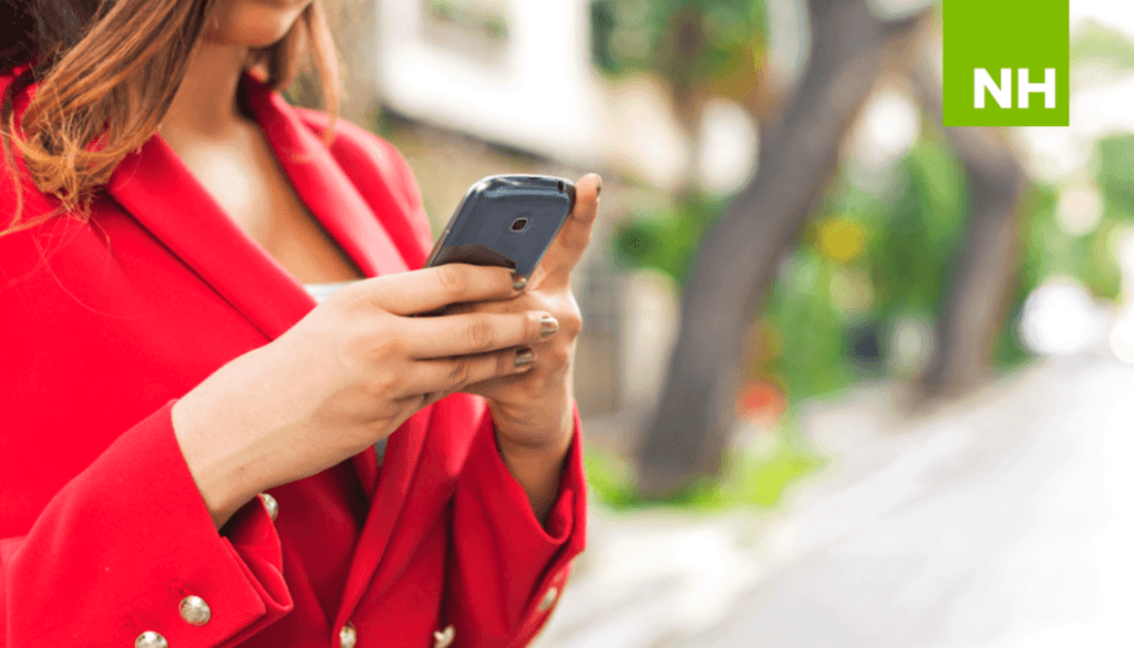 Woman in red jacket texting on cell phone