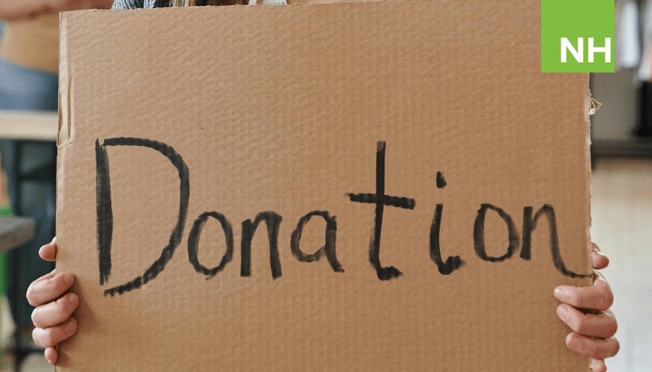 A woman holds a cardboard sign that has the word "Donor" written on it in sharpie.
